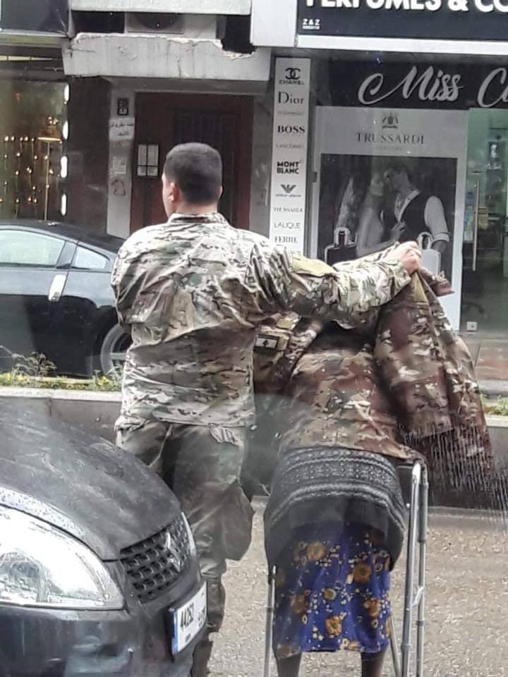 عسكري في الجيش يساعد عجوز مقعدة على عبور الشارع ويقيها من المطر بسترته واعجاب كبير بشهامته